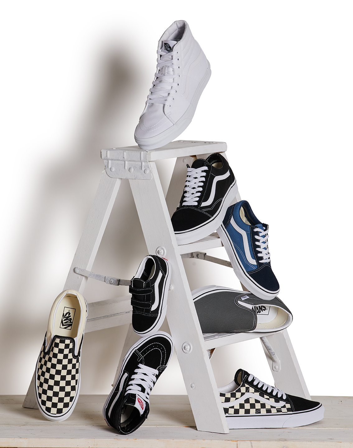 Assorted Vans sneakers that have been styled on a small white ladder by a professional footwear stylist
