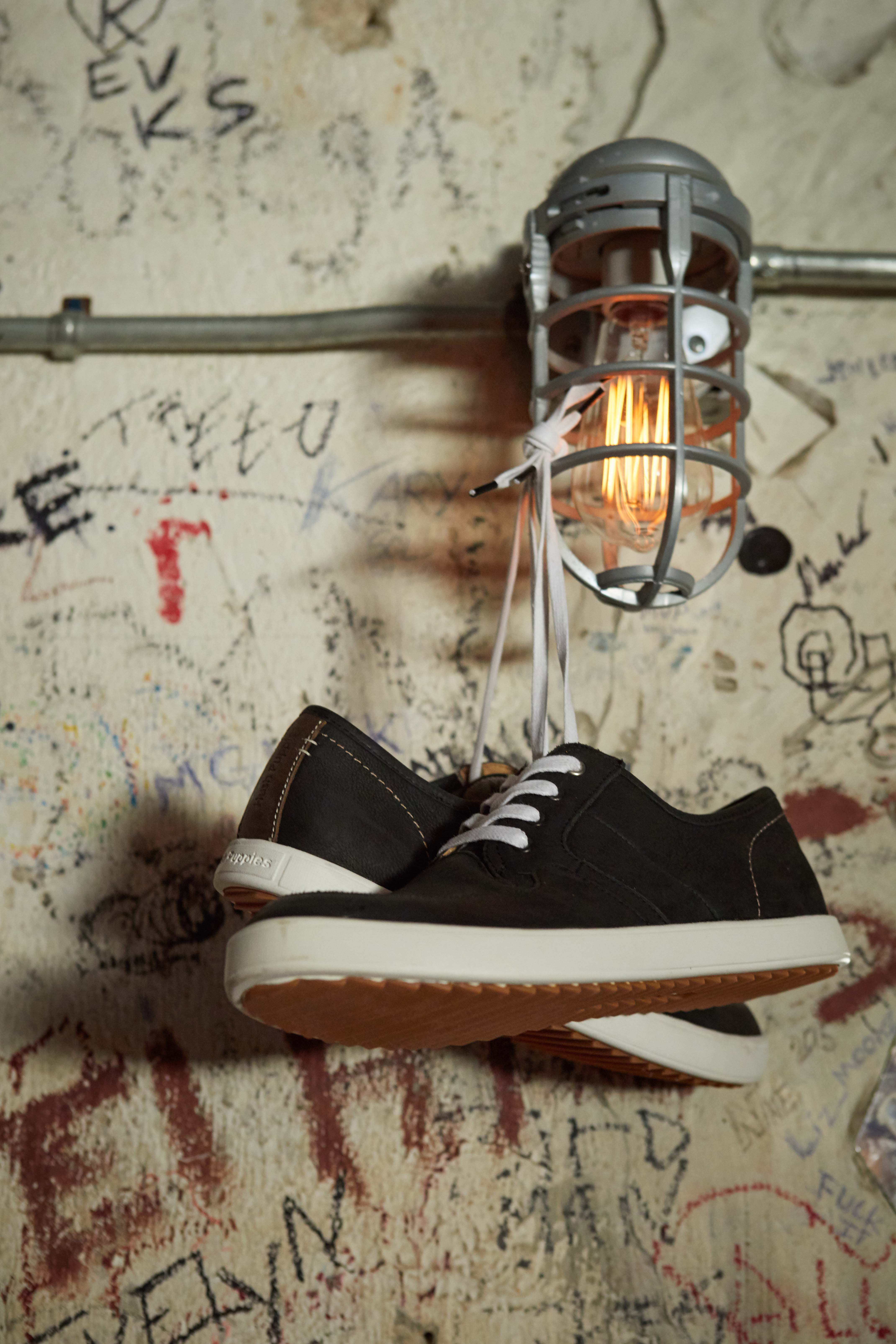 sneakers hanging from a light that have been styled by a footwear photo stylist